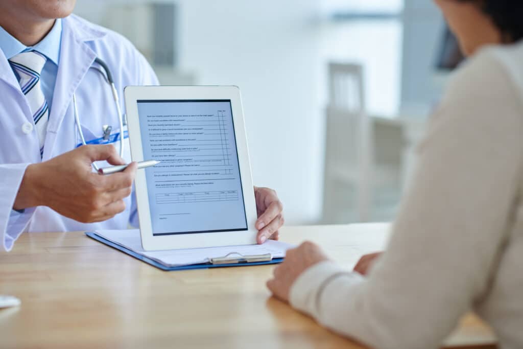 Doctor showing a digital tablet to a patient during a consultation in a clinic.