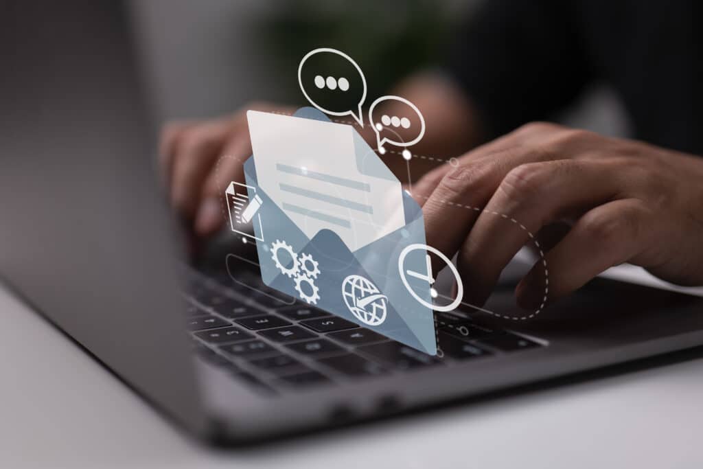 Person typing on a laptop with graphics of an envelope, speech bubbles, and gears overlayed, symbolizing digital communication and productivity.