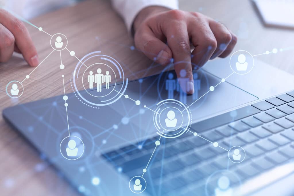 A person uses a laptop featuring a digital overlay of network connections and social media icons, highlighting modern communication technology.