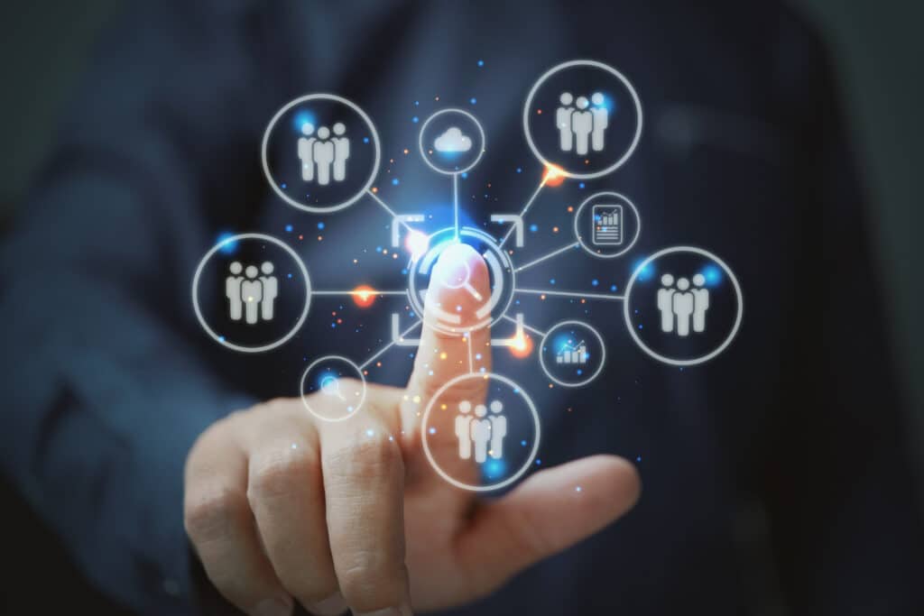 Person in a suit interacting with a futuristic holographic interface displaying network connections and human icons.